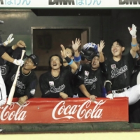 Lotte's Takashi Ogino is congratulated by his teammates after hitting a game-tying home run against Orix during the ninth inning in Kobe on Thursday. | KYODO