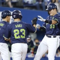 Yakult's Munetaka Murakami (right) is greeted by teammates after his first-inning grand slam against the BayStars on Tuesday in Yokohama. | KYODO