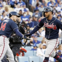 The Braves' Eddie Rosario crosses home plate after hitting a solo home run against the Dodgers in Los Angeles on Thursday. | KYODO