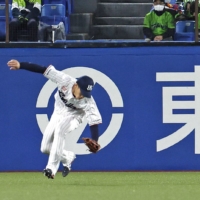 Swallows outfielder Yasutaka Shiomi makes an error in center field during the seventh inning against the Carp at Jingu Stadium on Thursday. Three runs scored on the play. | KYODO