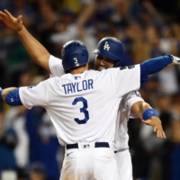 Chris Taylor hugs teammate Albert Pujols after hitting a two-run home run against the Braves during the fifth inning in Game 5 of the NLCS on Thursday. | USA TODAY / VIA REUTERS