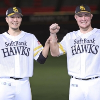 The Hawks' Kodai Senga (left) and Richard Sunagawa pose for photos after the team's win over the Buffaloes in Fukuoka on Sunday. | KYODO