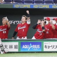 Carp players greet Koki Ugusa (left) after his leadoff home run against the Giants on Saturday at Tokyo Dome. | KYODO