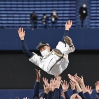 Orix Buffaloes players toss manager Satoshi Nakajima into the air at Tokyo Dome after the team clinched the Pacific League pennant on Wednesday. | KYODO