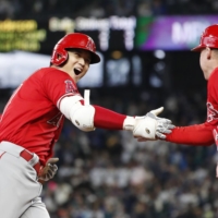 Shohei Ohtani celebrates with the Angels third base coach after hitting a home run against the Mariners in the first inning in Seattle on Sunday. | KYODO