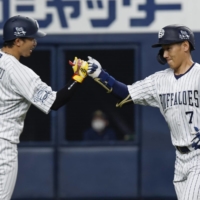 Masataka Yoshida (right) is greeted by Buffaloes teammate Ryoichi Adachi after his home run against the Lions in Osaka on Saturday. | KYODO