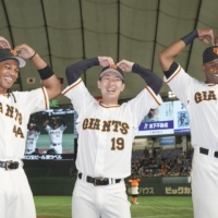 The Giants' Adam Walker (left) and Gregory Polanco (right) pose with teammate Iori Yamasaki after a game at Tokyo Dome on May 18. | KYODO