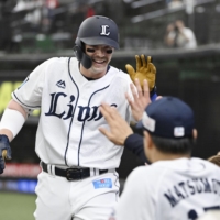 Brian O'Grady celebrates with his teammates after hitting solo home run against the Carp in the first inning on Sunday. | KYODO
