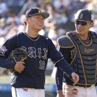 Orix pitcher Yoshinobu Yamamoto (left) returns to the bench with battery partner Kenya Wakatsuki after the eighth inning of their game against the Marines in Chiba on Saturday. | KYODO