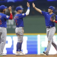 Cubs outfielder Seiya Suzuki (right) high fives teammates following their win over the Brewers in Milwaukee, Wisconsin, on Tuesday. | USA TODAY / VIA REUTERS