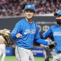 Fighters pitcher Naoyuki Uwasawa (left) returns to the dugout after the seventh inning of his team's game against the Lions in Sapporo on Saturday. | KYODO