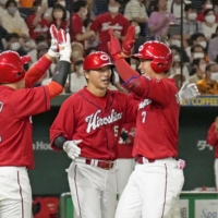 Carp infielder Shota Dobayashi (right) is greeted by teammates after his grand slam against the Giants at Tokyo Dome on Sunday. | KYODO