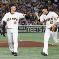Giants pitcher Iori Yamasaki (left) and infielder Raito Nakayama celebrate while leaving the field after the third inning of their win over the Tigers at Tokyo Dome on Thursday. | KYODO