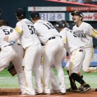 SoftBank outfielder Ukyo Shuto (second from right) is greeted at home plate by his teammates after hitting a walk-off home run against Orix in Fukuoka on Saturday. | KYODO