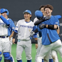Yushi Shimizu (right) hugs one of his teammates after his game-winning hit against the Lions at Sapporo Dome on Thursday. | KYODO