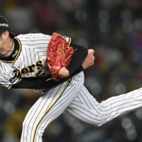 The Tigers' Hiroto Saiki pitches against the Carp in Nishinomiya, Hyogo Prefecture, on Thursday. | KYODO