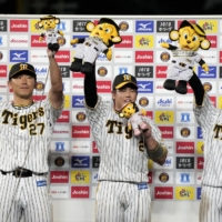 The Tigers' Masashi Ito (left) Ryutaro Umeno (center) and Koji Chikamoto celebrate after their win over the Swallows in Nishinomiya, Hyogo Prefecture, on Wednesday. | KYODO