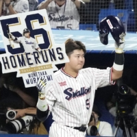 Munetaka Murakami holds up a sign after hitting his 56th home run of the season for the Swallows at Jingu Stadium on Monday. | KYODO