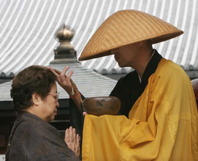 Une femme prie après avoir fait une offrande à un moine bouddhiste dans un temple de Tokyo le 17 septembre 2006.