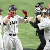 Kazuma Okamoto is (center) is congratulated by Shohei Ohtani after hitting a three run home run for Samurai Japan during the third inning of its game against Italy at Tokyo Dome on Thursday. | KYODO
