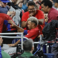 Puerto Rico pitcher Edwin Diaz (seated) leaves the field on a wheelchair after an apparent leg injury during the team celebration following a WBC win againt the Dominican Republic at LoanDepot Park in Miami on Wednesday. | USA TODAY / VIA REUTERS
