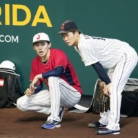 Samurai Japan pitcher Roki Sasaki (left) and Yoshinobu Yamamoto talk during practice in Miami on Sunday. | KYODO