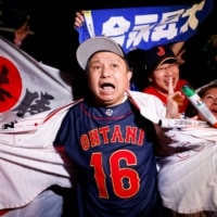 Fans react in Tokyo on Wednesday after Japan won against the United States in the World Baseball Classic final. | REUTERS