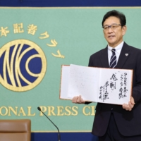 Hideki Kuriyama poses for photos during a news conference at the Japan National Press Club on Monday. | KYODO