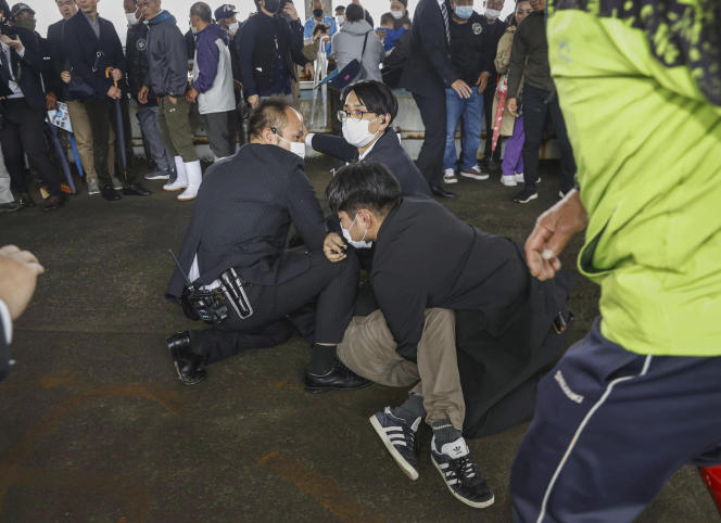 Un homme immobilisé au sol par la police, suspecté d’avoir jeté une bombe fumigène sur le premier ministre japonais, Fumio Kishida, dans le port de pêche de Wakayama, au Japon, le 15 avril 2023.
