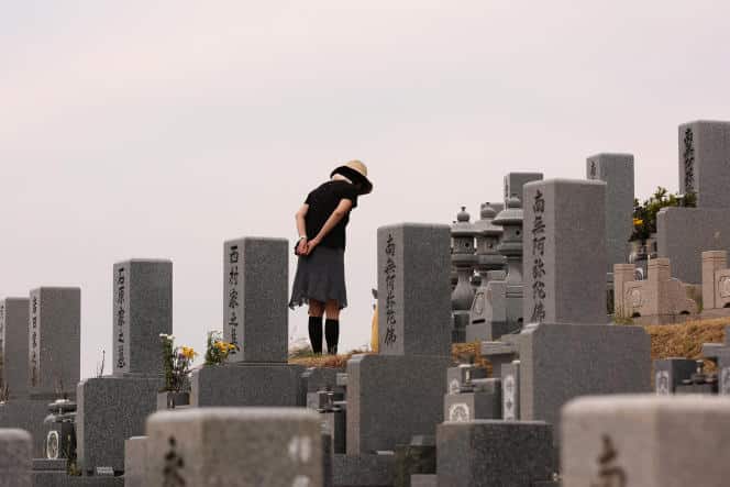 Une femme prie devant la tombe de son ancêtre, au cimetière de Nagoyama, le 13 août 2016, à Himeji, au Japon.