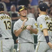Masashi Ito (center) celebrates with his Tigers teammates after their win over the Giants at Tokyo Dome on Saturday. | KYODO
