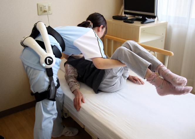 Une infirmière utilise la combinaison robotique Hybrid Assistive Limb (HAL) de Cyberdynede pour s’aider à soulever une patiente âgée à la maison de retraite Fuyoen, à Yokohama, dans la banlieue de Tokyo, en 2015.