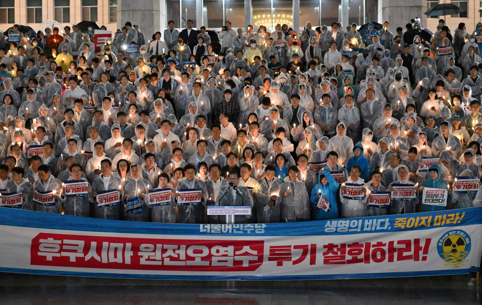 Des membres du Parti démocrate, principal parti d’opposition en Corée du Sud, tiennent des bougies électriques et des pancartes sur lesquelles on peut lire « Annulez le déversement de l’eau contaminée de Fukushima ! », lors d’un rassemblement contre le projet du Japon de rejeter les eaux traitées de la centrale nucléaire de Fukushima dans l’océan, devant l’Assemblée nationale à Séoul, le 23 août 2023. 