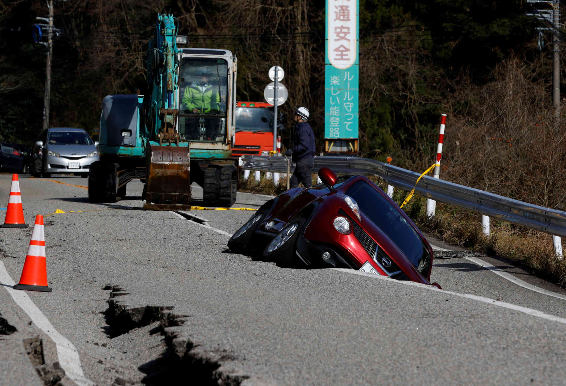 Vue d’une voiture coincée dans une fissure de la route, près d’Ujima, dans la préfecture d’Ishikawa, au Japon, le 2 janvier 2024.
